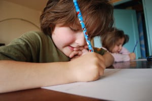 A boy writes on paper with a fun pencil