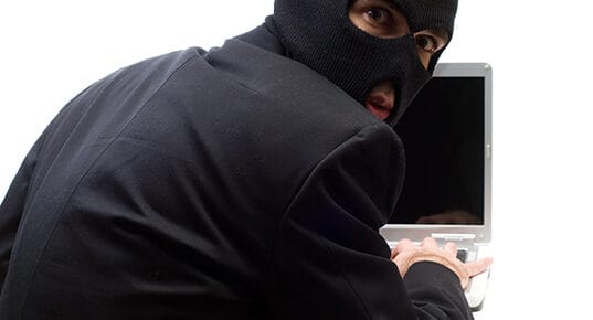 A thief looks over his shoulder while hacking a computer
