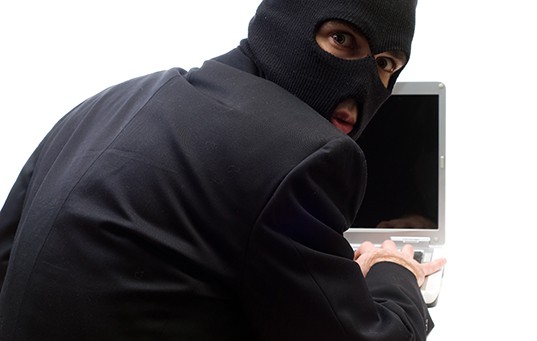A thief looks over his shoulder while hacking a computer
