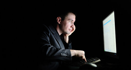A man looking happily at a computer monitor