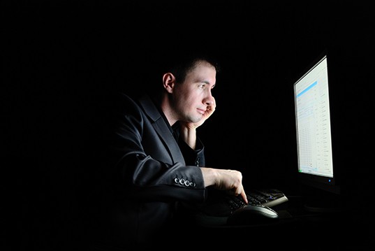 A man looking happily at a computer monitor