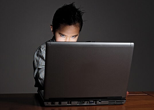 Little boy looking above laptop screen