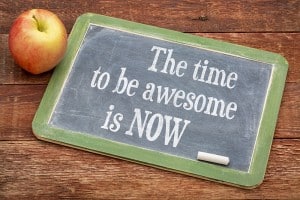 The time be awesome is now - motivational words on a slate blackboard against red barn wood