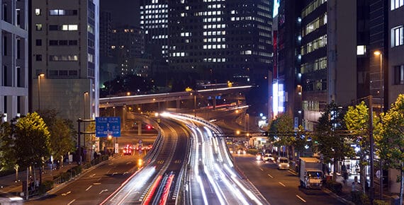 Traffic streaks down a city road at night