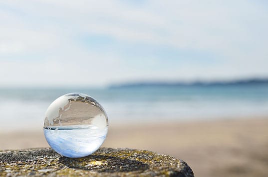 A clear glass globe rests near the beach