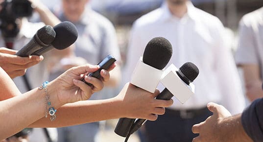 Reporters hold out microphones for interview