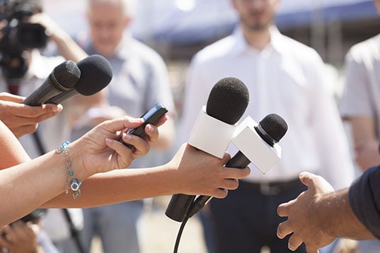 Reporters hold out microphones for interview